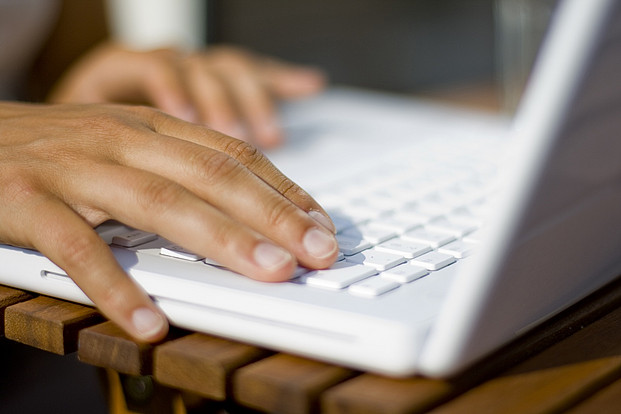 Rufen Sie uns an um Ihre Spenderdaten wegen z.B. Umzug oder Bankwechsel zu ändern. Hände auf Laptop-Tastatur